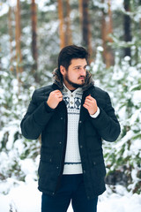 portrait of a young man in the woods in the winter, down jacket