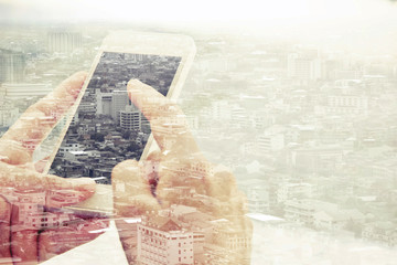  Double exposure of using smart phone and cityscape background ,Business technology concept. 