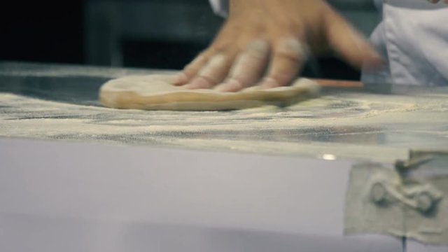 Chef kneads the dough, forming a pizza cake