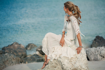 Fototapeta premium beautiful boho woman on stone at sea shore