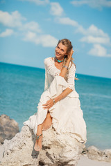 beautiful boho woman on stone at sea shore