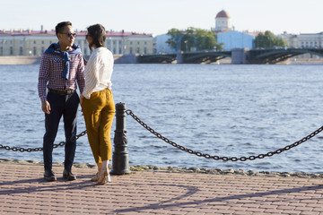A loving couple walk on embankment of a river "Neva". Portrait of a man and woman are outdoors in St. Petersburg.  