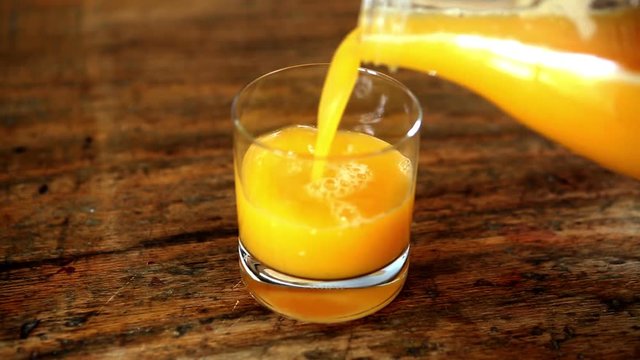 closeup of orange juice being poured in a glass and bottle next to it
