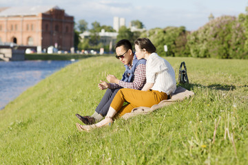 A loving couple is sitting on the grass. Portrait of a man and woman are outdoors in St. Petersburg. 
