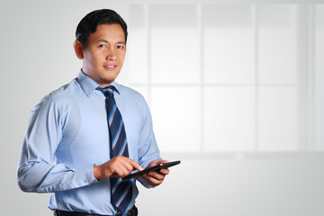 Young Businessman Smiling and Touching a Tablet