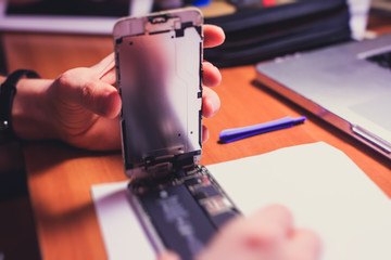 A close-up process of disassemble and dismantle modern mobile phone smartphone with broken shattered display glass and changing details at home
