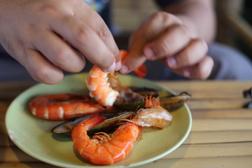 Hand of man peeled shrimps on the plate