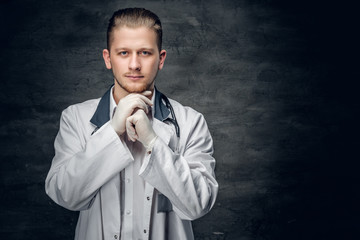 Portrait of confident young medical doctor on grey background.