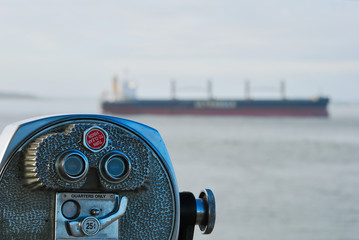 Public telescope with background ocean freighter