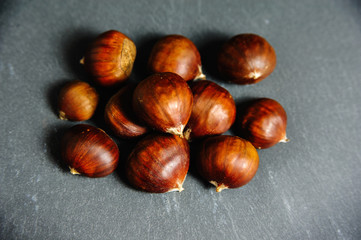 raw edible chestnuts close up on slate background. top view