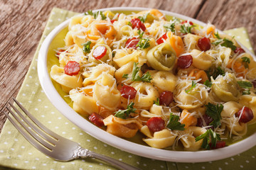 Italian colored tortellini with parmesan and sliced sausages close-up. Horizontal
