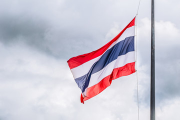 Thai flags half-mast on cloudy storm background.