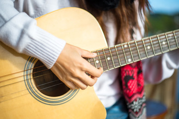 Woman's hands playing acoustic guitar, close up