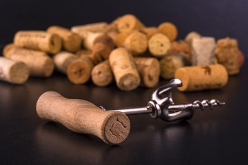 Wine corks and corkscrew on black  table