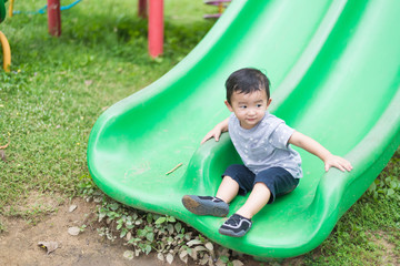 Fototapeta na wymiar Little Asian kid playing slide at the playground