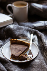 Chocolate cake and cappuccino on a woolen rug, focus on front of cake, toning