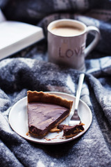 Chocolate cake and cappuccino on a woolen rug, focus on front of cake, toning