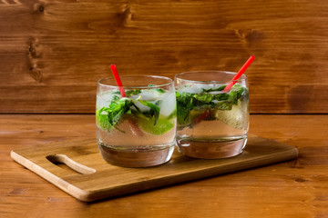 Two mojito cocktails with lime and mint in a glass on the table