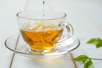 Warm cup of tea and leaves tea on white wooden