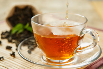 Warm cup of tea and leaves tea on white wooden