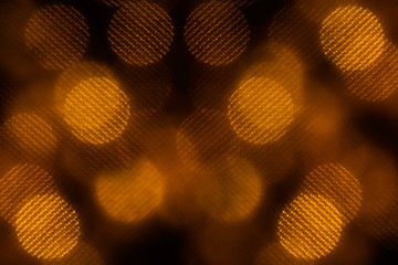 Bokeh dark orange mesh circles on black background. Abstract festive background.