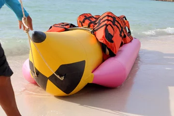 Papier Peint photo Sports nautique Main d& 39 homme avec bateau banane et gilet de sauvetage sur la plage