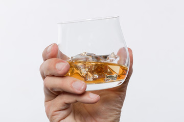 Hand hält Whiskeyglas mit Whiskey auf Eis