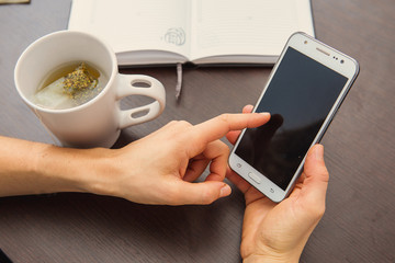 ragazza con tazza, cellulare e agenda sul tavolo