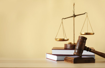 Justice scales, judge's gavel and books on wooden table and beige background