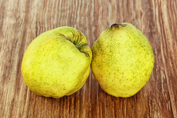 Two appetizing ripe quince on grunge wooden background.