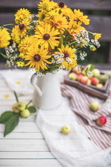 Obraz na płótnie Canvas Still, yellow flowers with a vase with apples