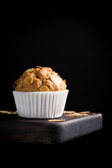 Delicious homemade coconut cinnamon muffin with almond flakes on black background. Healthy food concept with copy space.