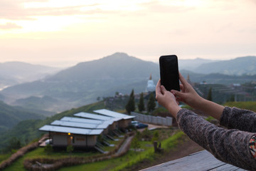 Young woman take photo of mountain view by smart phone in morning.