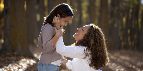 Madre e hija sonriendo en el bosque