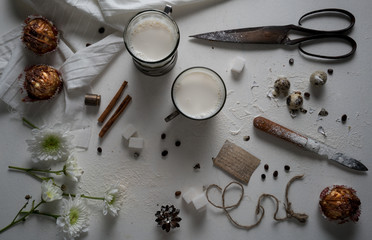 Fototapeta na wymiar milk and yogurt cups, cake, vanilla, chrysanthemum on the table. top view