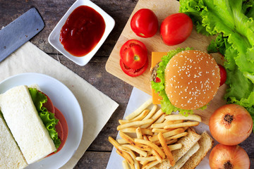 Grilled beef hamburger with vegetables on wood table, over light