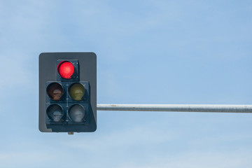 Traffic lights on red against blue sky background.