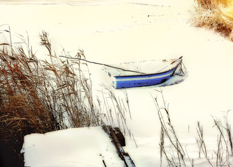 Boat abandoned on the frozen river. Snowy winter landscape frost early in the morning,   
natural vintage hipster background, soft focus
