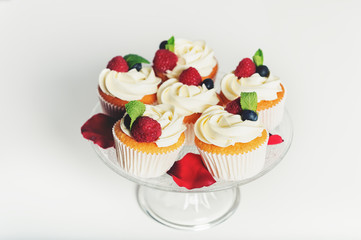 Cupcakes decorated with fresh berries and mint on glass tray