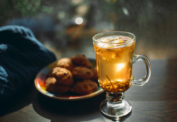 Autumn Still Life: Herbal tea on a wooden table near the window. The sun's rays on a cup of brewed tea. A cup of hot chayas pichenem on a sunny day on the background of the window. Autumn tea