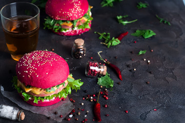 Closeup of homemade burgers with lettuce and sausage on a black wooden background