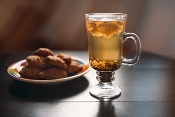 Autumn Still Life: Herbal tea on a wooden table near the window. The sun's rays on a cup of brewed tea. A cup of hot chayas pichenem on a sunny day on the background of the window. Autumn tea