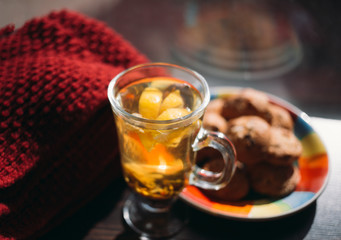 Autumn Still Life: Herbal tea on a wooden table near the window. The sun's rays on a cup of brewed tea. A cup of hot chayas pichenem on a sunny day on the background of the window. Autumn tea