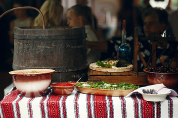 Brown bowls with pickled vegetables and meat stand on the embroi