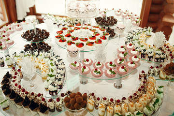 Pieces of cakes decorated with fruits stand on curved glass dish