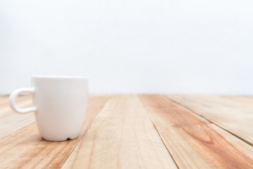 White cup on wooden table and cement wall background,Soft focus