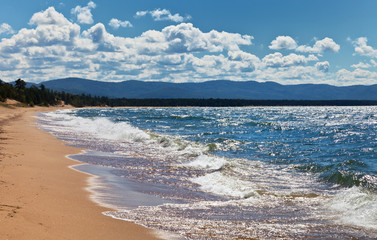 Baikal Lake. The waves on a sandy beach sparkle on the sun in windy day