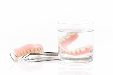 close up of dentures in glass of water and dental tool with noti
