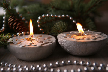 Silver Christmas candles decorated with snowflakes near christmas tree, garlands.  Candlelight.