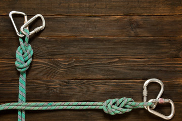 frame of climbing rope and carabiners on dark wooden background,